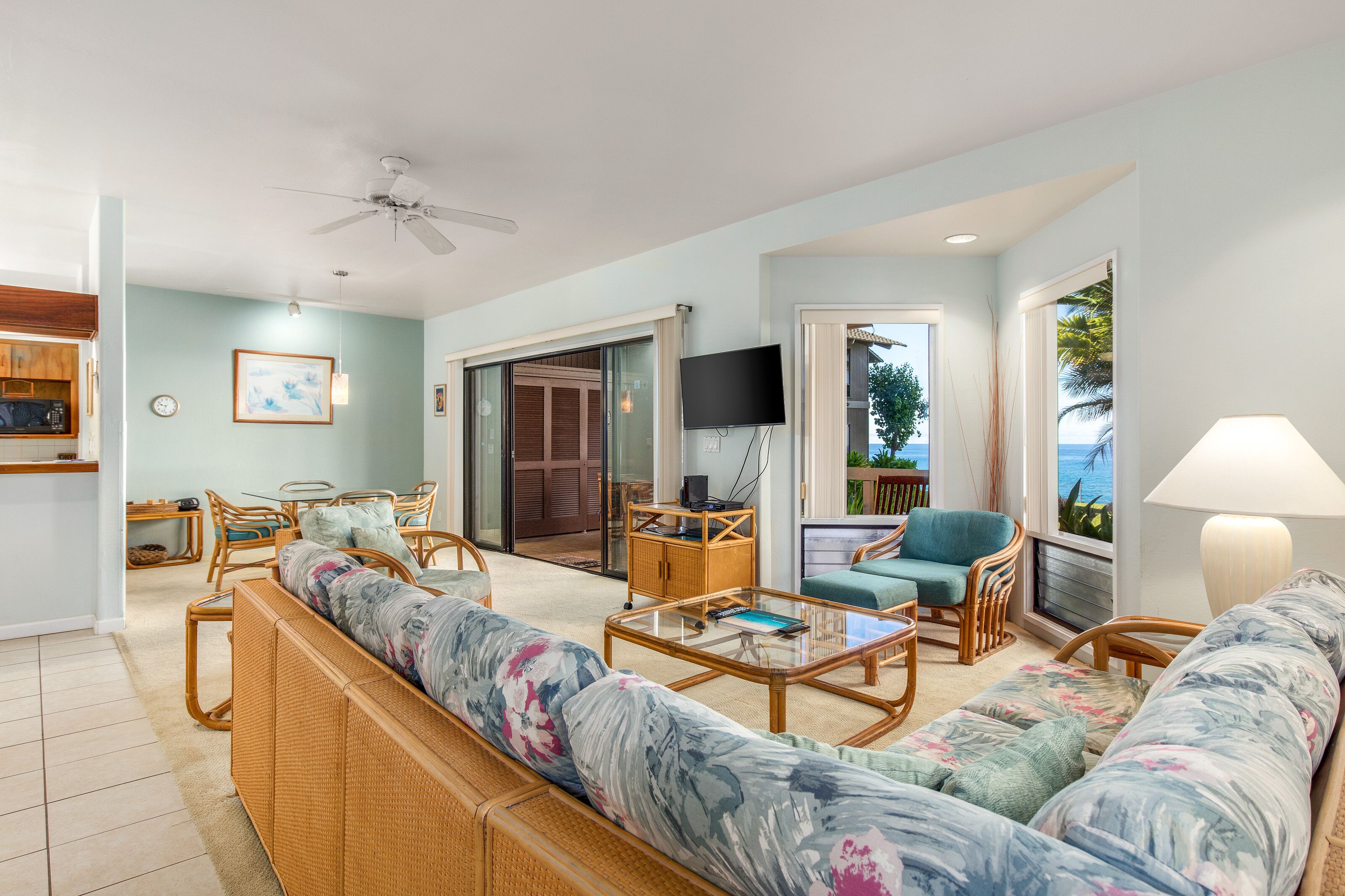 A spacious living room with a sofa, coffee table, and chairs, a television, and a view of the outdoors.