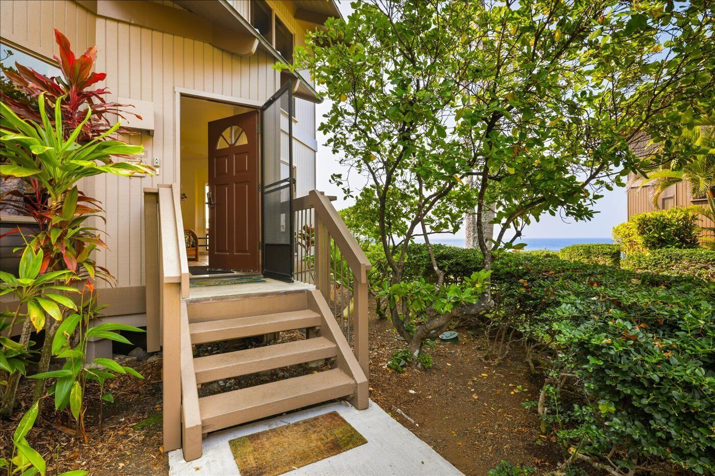 Ein Holzhaus mit einer Veranda, einer Treppe und Blick auf den Ozean.