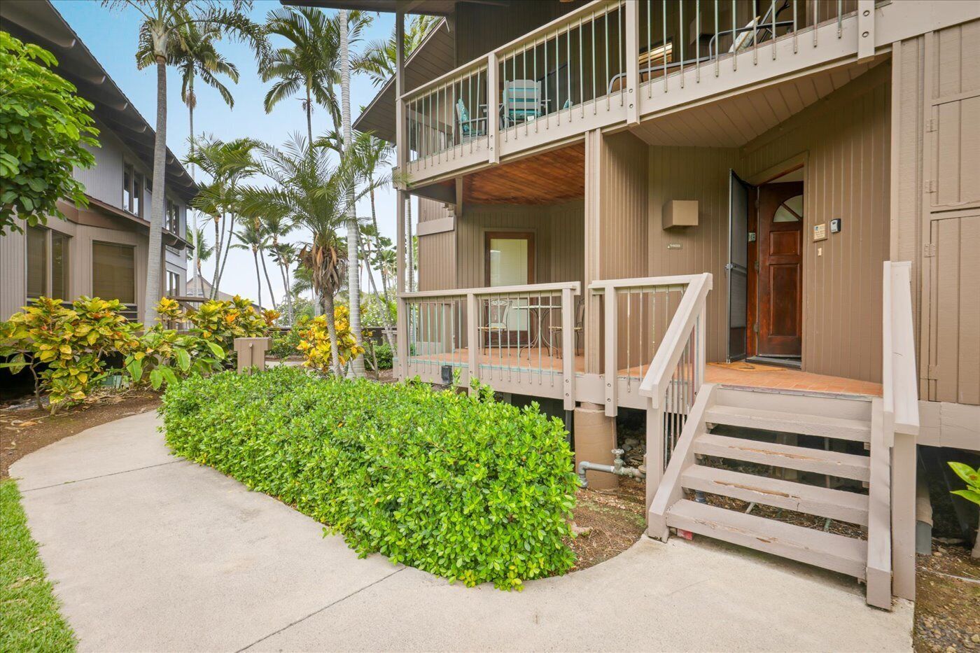 A two-story building with a balcony, a covered porch, and a pathway leading to the entrance.