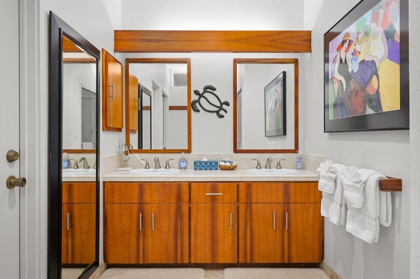 Un baño con armarios de madera, un lavamanos doble y un perchero para toallas.