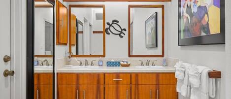 Un baño con armarios de madera, un lavamanos doble y un perchero para toallas.