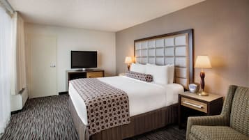 A hotel room with a large bed, two bedside lamps, a flat-screen TV, a chair, and a dresser.