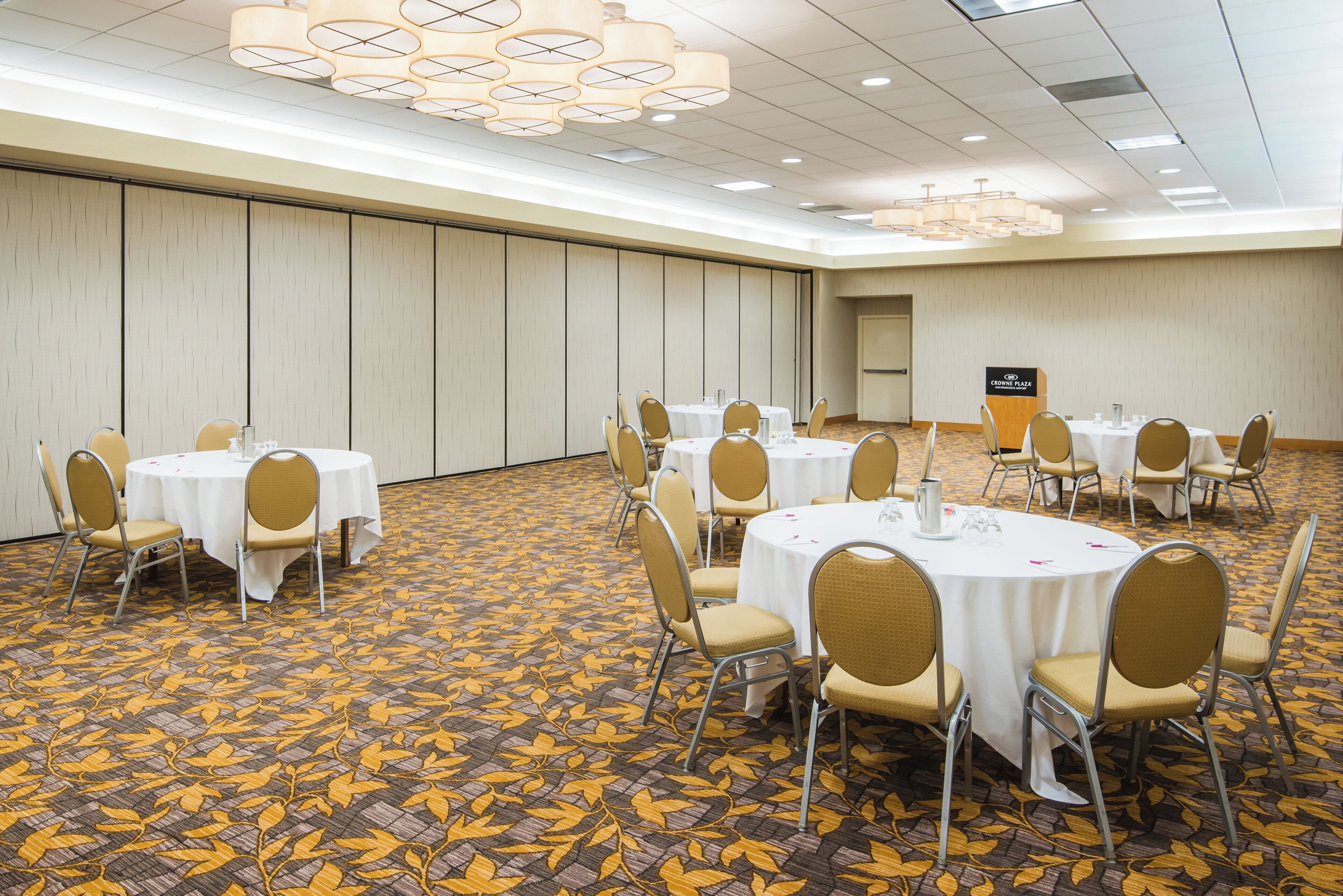 A conference room with round tables, chairs, and a podium.