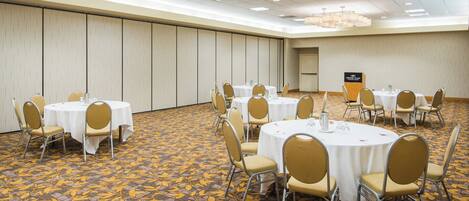 A conference room with round tables, chairs, and a podium.