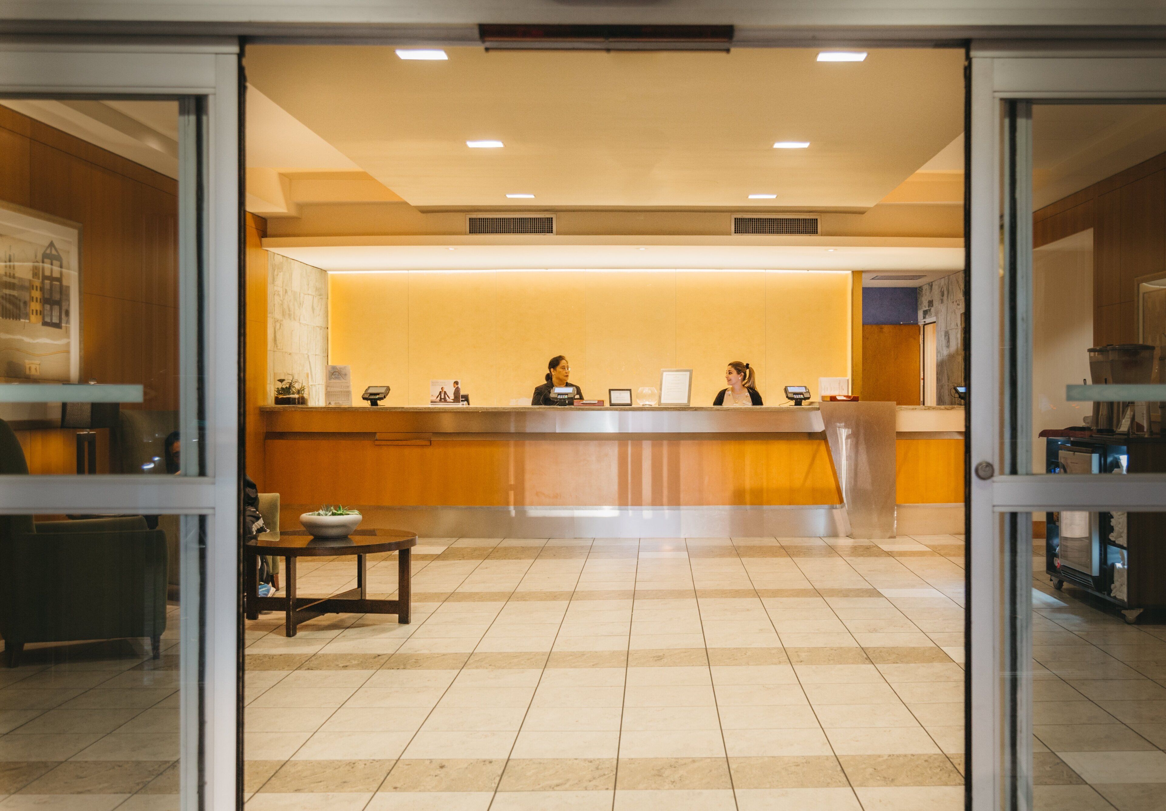 A reception area with a counter, chairs, a small table with a bowl, and a tiled floor.