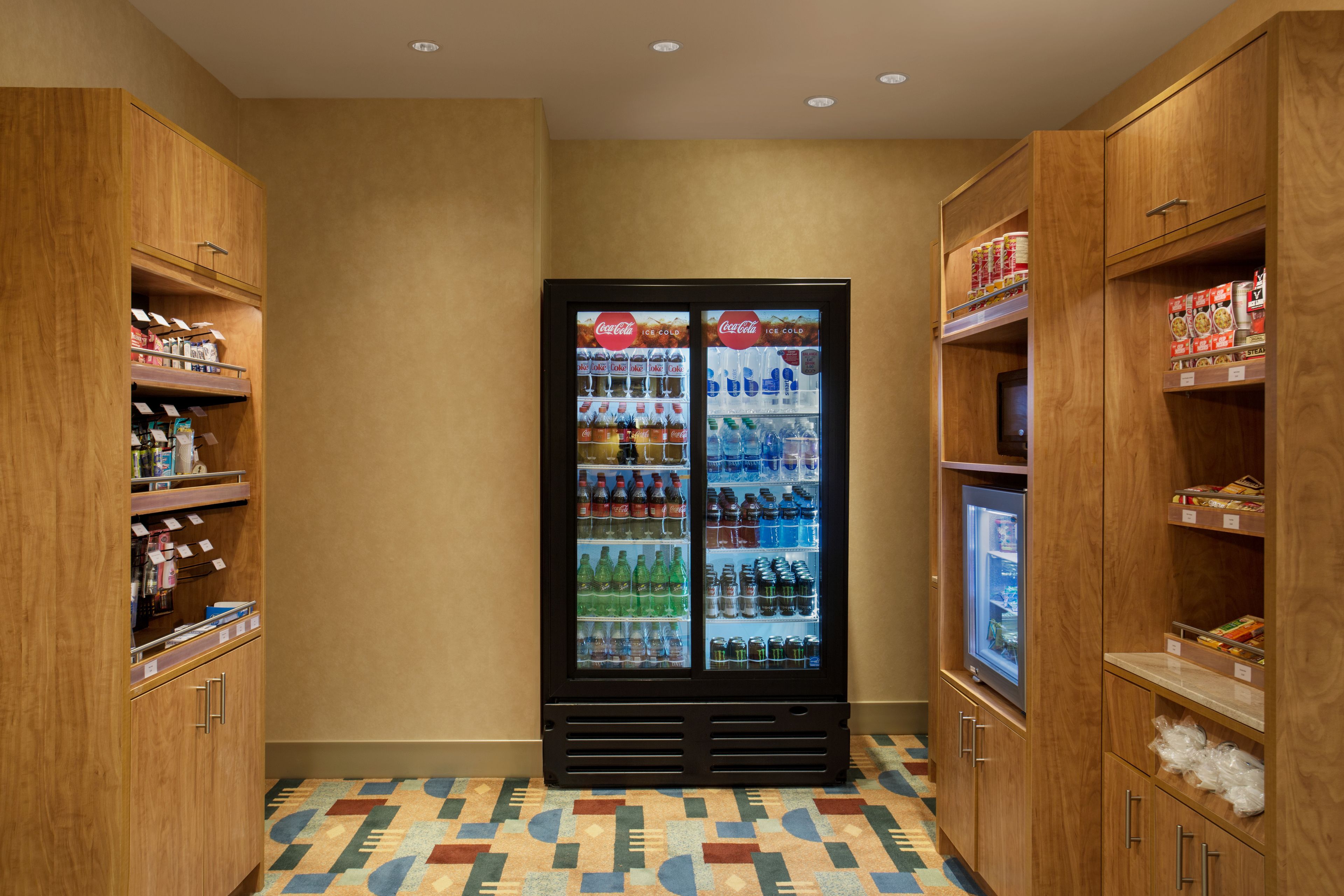 Ein Hotelzimmer mit Holzausstattung, einem gemusterten Boden und einem Coca-Cola Kühlschrank.