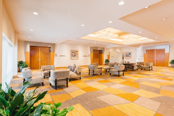 A hotel lobby with a checkered carpet, multiple seating areas, and wooden doors labeled "BATHROOM 1" and "BATHROOM 2". - Crowne Plaza San Francisco Airport by IHG (Burlingame)