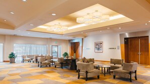 A spacious lobby with a checkered floor, multiple seating areas, and a large wooden door.