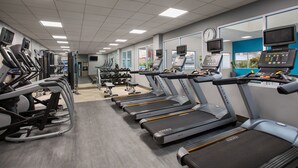 Une salle de sport équipée de tapis de course, de vélos d’exercice et d’appareils de musculation.