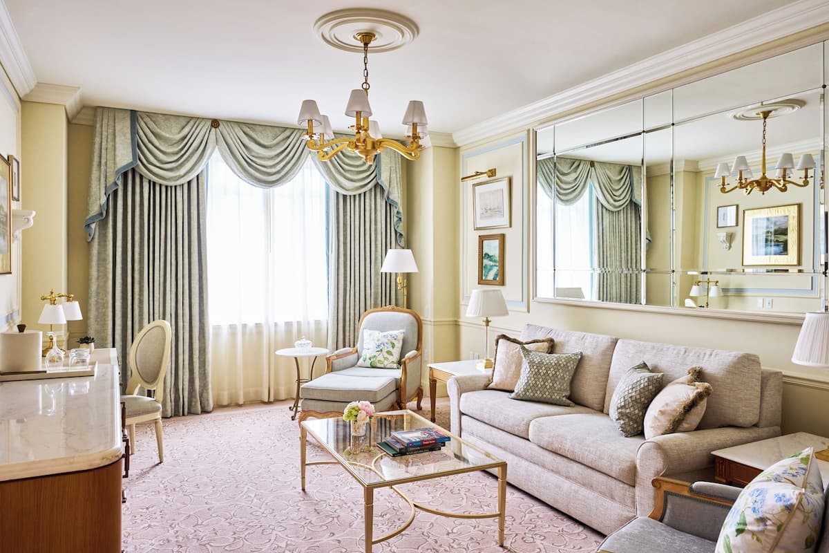 A well-appointed living room with a sofa, armchairs, a coffee table, and a large mirror.