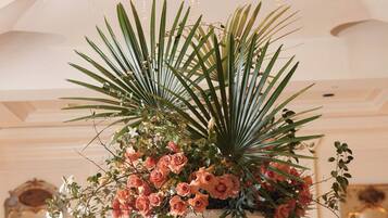 A round table with a floral centerpiece, a chandelier, and a mirror in the background.