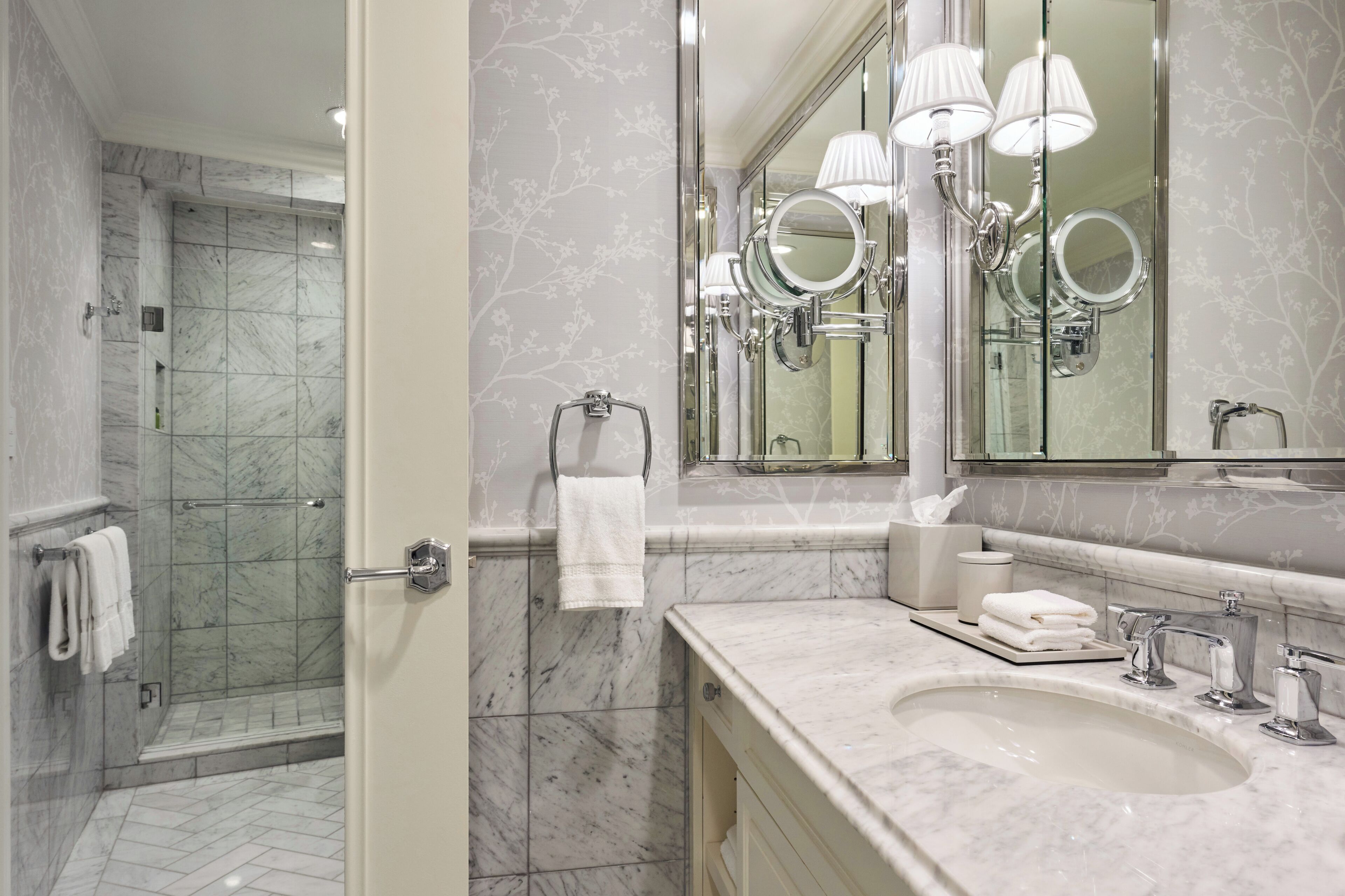 A bathroom with a shower, a sink, and a mirror with lights.