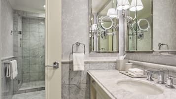 A bathroom with a shower, a sink, and a mirror with lights.