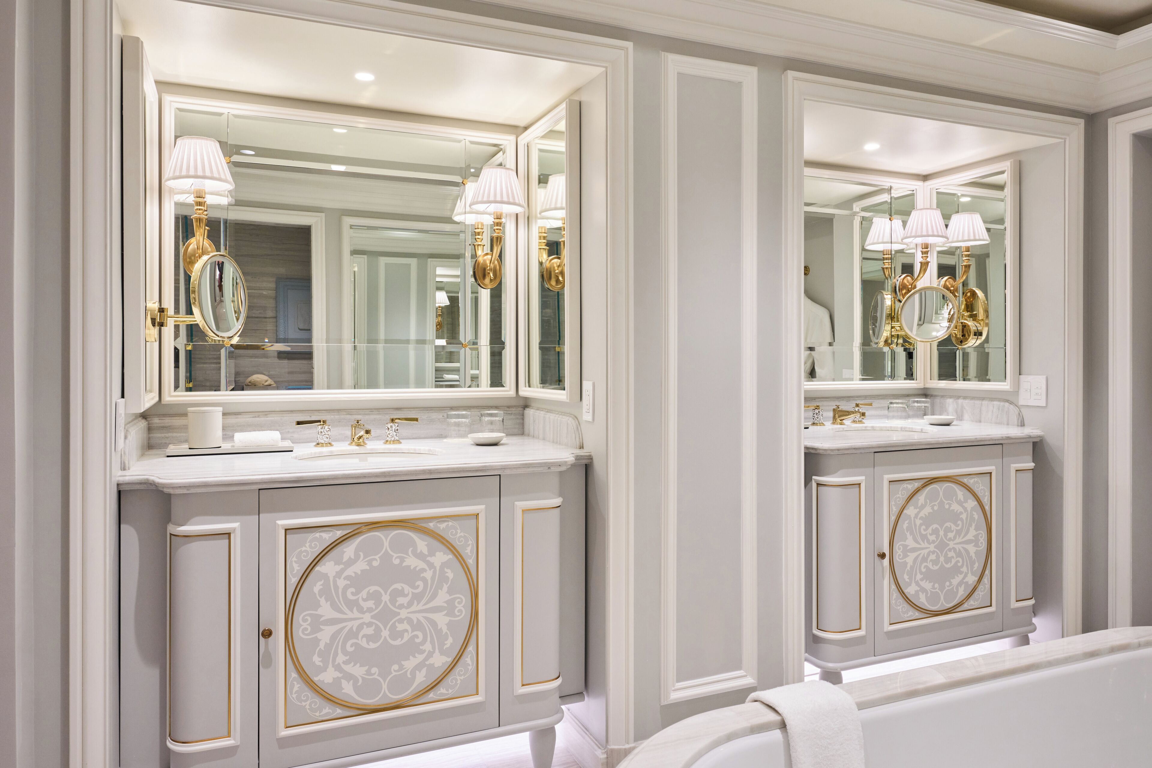 Ein Badezimmer mit zwei Waschbecken, großen Spiegeln und goldenen Armaturen.
