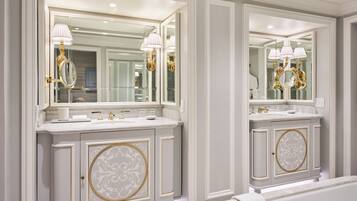 Ein Badezimmer mit zwei Waschbecken, großen Spiegeln und goldenen Armaturen.