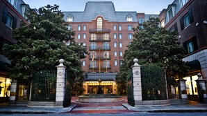 A large, multi-story hotel with a central entrance, surrounded by trees and featuring a prominent entrance gate. - The Charleston Place (Charleston)