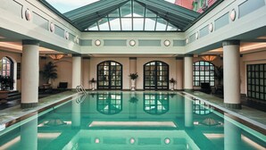 A large indoor swimming pool with a glass ceiling, surrounded by columns and potted plants. - The Charleston Place (Charleston)