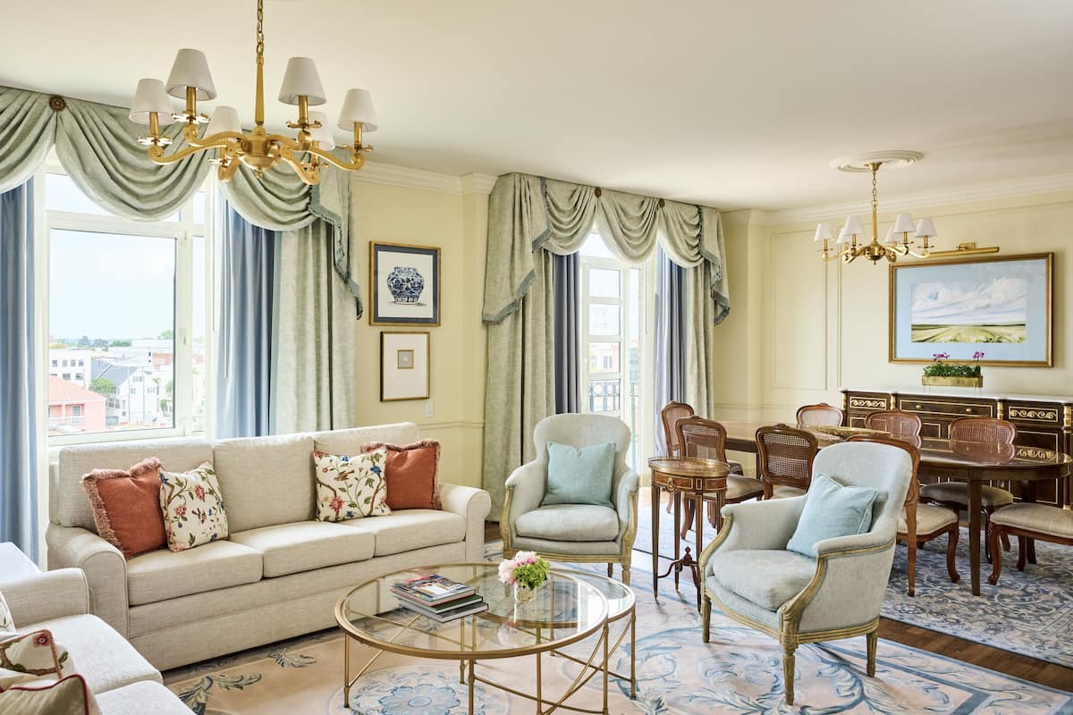 A well-furnished living room with a sofa, armchairs, a coffee table, and a dining area with chairs and a table.