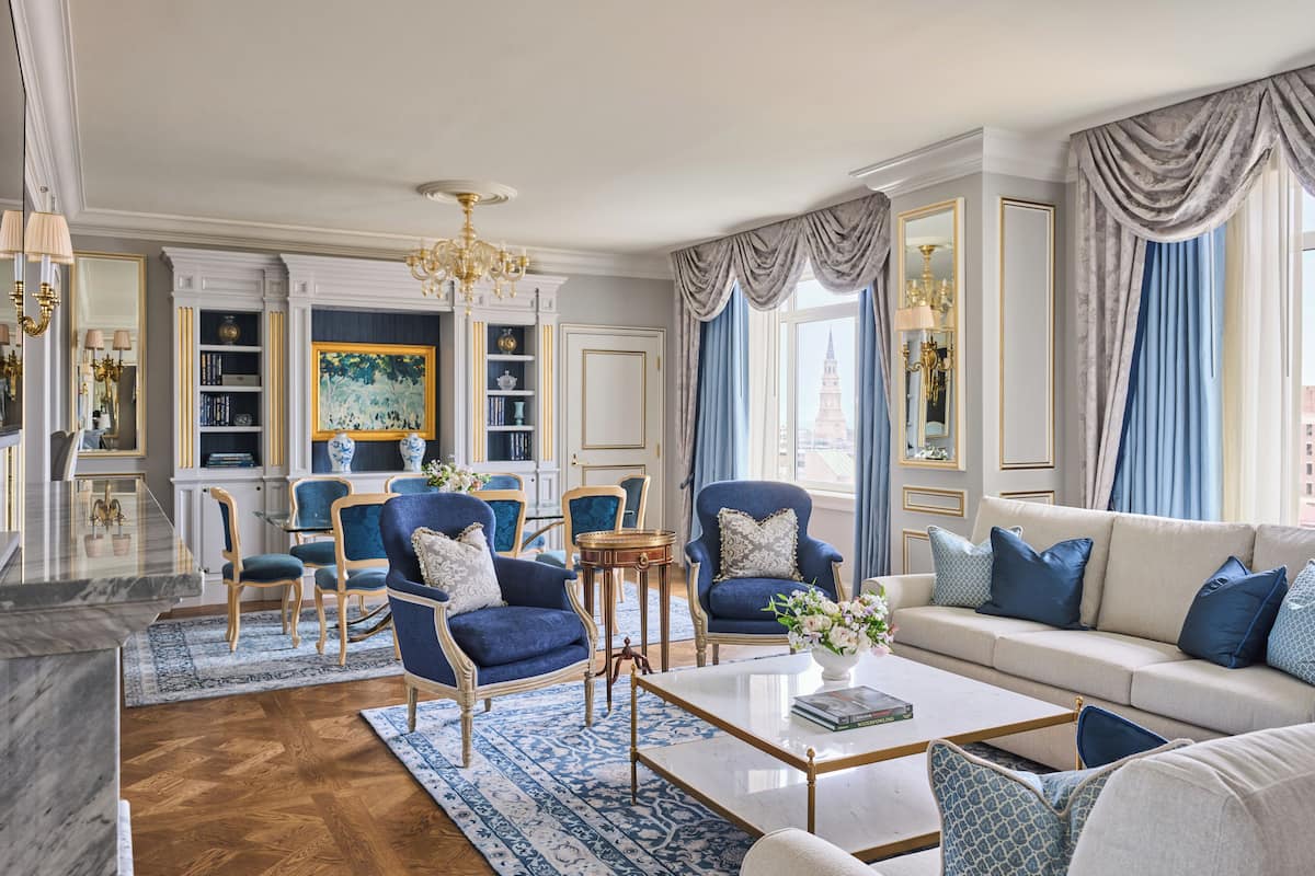 A spacious living room with a sofa, armchairs, a coffee table, and a bookshelf.