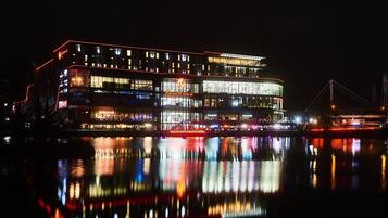 A multi-story hotel with illuminated signage and a reflection on the water.