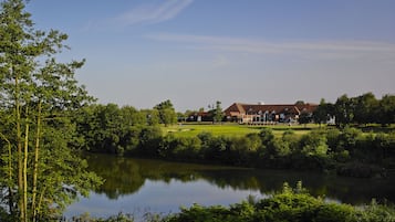 A golf course with a clubhouse, a pond, and surrounding greenery.