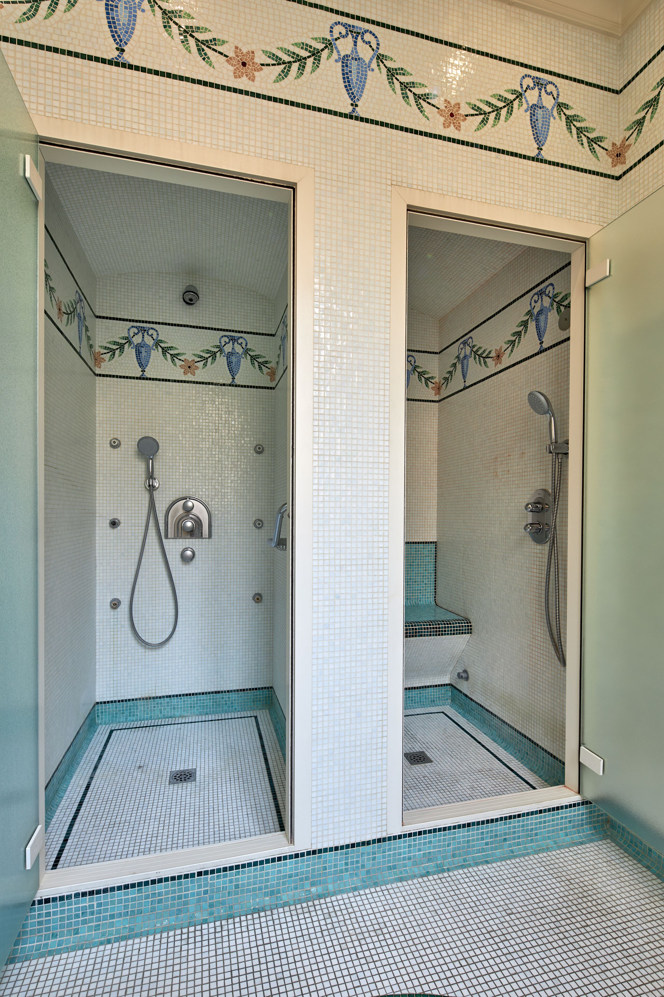 Une salle de bain avec un espace douche, des murs carrelés et un drain.
