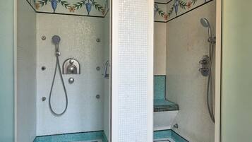 Une salle de bain avec un espace douche, des murs carrelés et un drain.