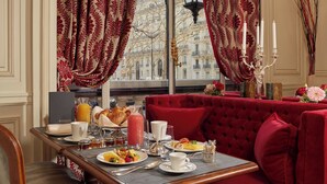 A breakfast setting with a table set for two, featuring croissants, fruit, and a drink.