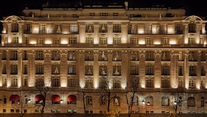 A large, illuminated hotel facade with multiple balconies and large windows.