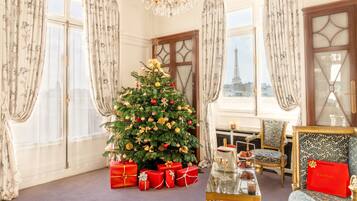 Une pièce décorée d’un sapin de Noël, dotée de grandes fenêtres, d’un lustre et offrant une vue sur la Tour Eiffel.