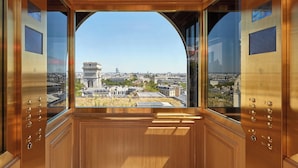 An elevator with a large arched window offering a view of a cityscape, including a prominent tower.