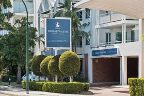A sign for Broadwater Resort Como with a view of the building's architecture and landscaping.