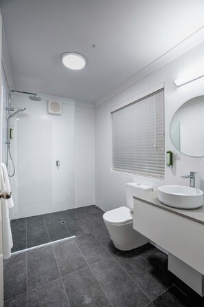A modern bathroom with a shower, toilet, and sink.
