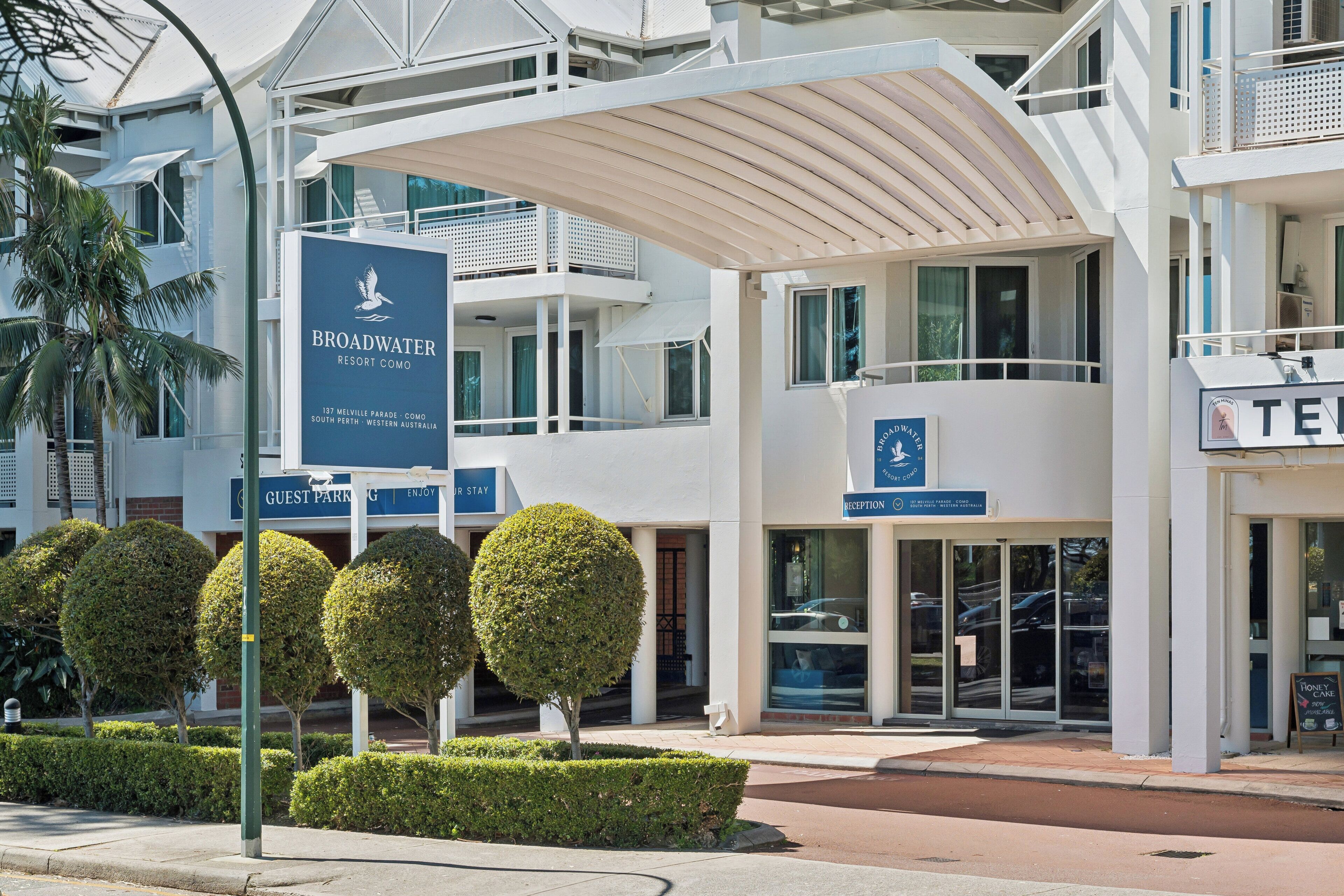 L’entrée d’un hôtel, avec une enseigne indiquant « Broadwater Resort Como », un espace de réception et un panneau indiquant l’emplacement du parking réservé aux clients.