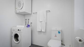 A modern bathroom with a washing machine, a toilet, and a towel rack.