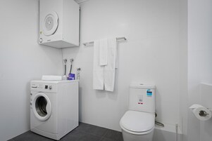 Ein modernes Badezimmer mit Waschmaschine, Toilette und Handtuchhalter.