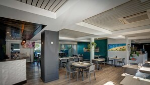 A modern restaurant with high ceilings, a central column, and a mix of round and rectangular tables. - Broadwater Resort Como (Como)