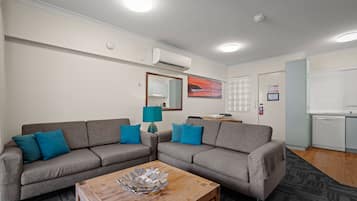 Ein modernes Wohnzimmer mit zwei grauen Sofas, einem Holztisch und einer blauen Lampe.