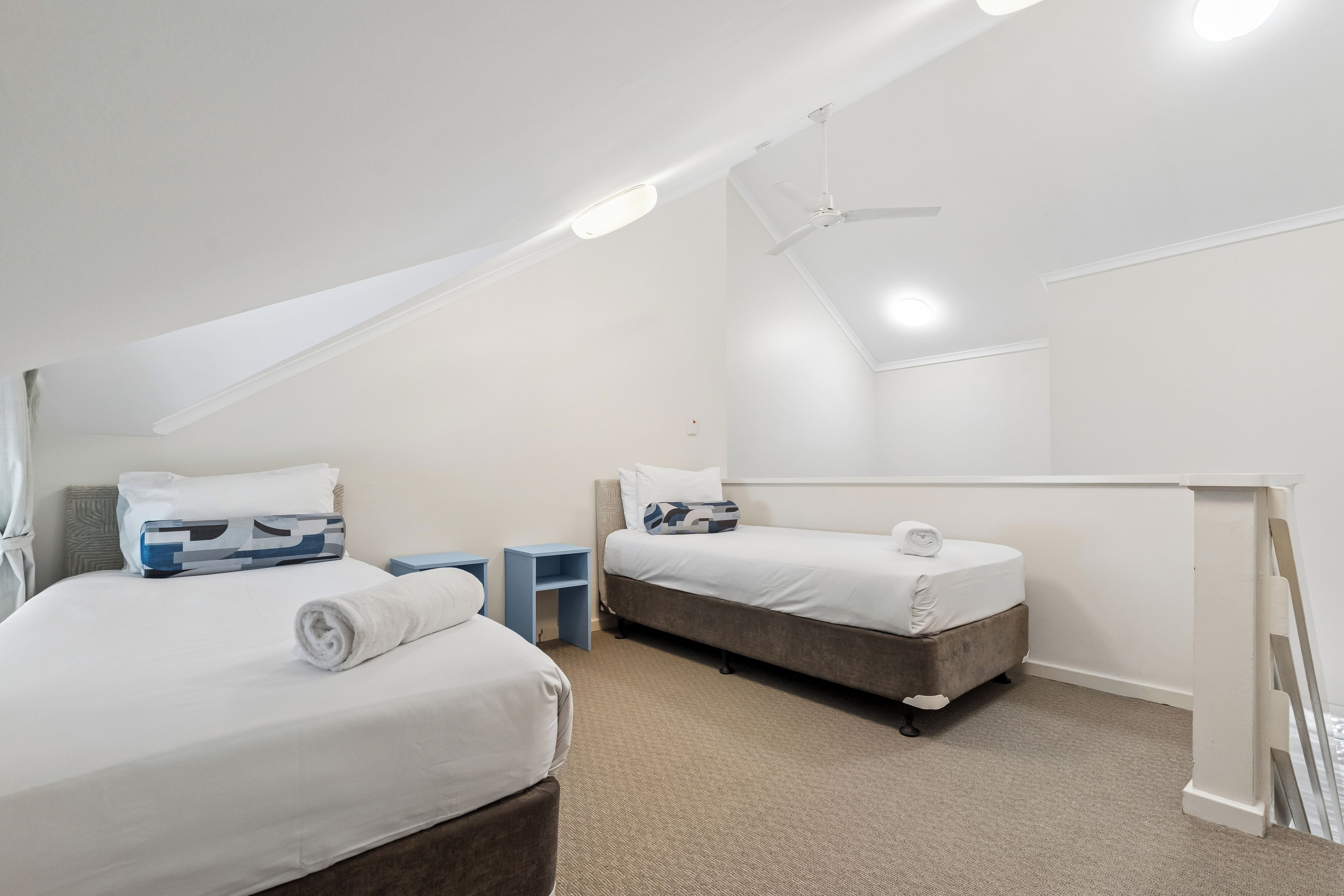 Een hotelkamer met twee bedden, een plafondventilator en een groot raam.