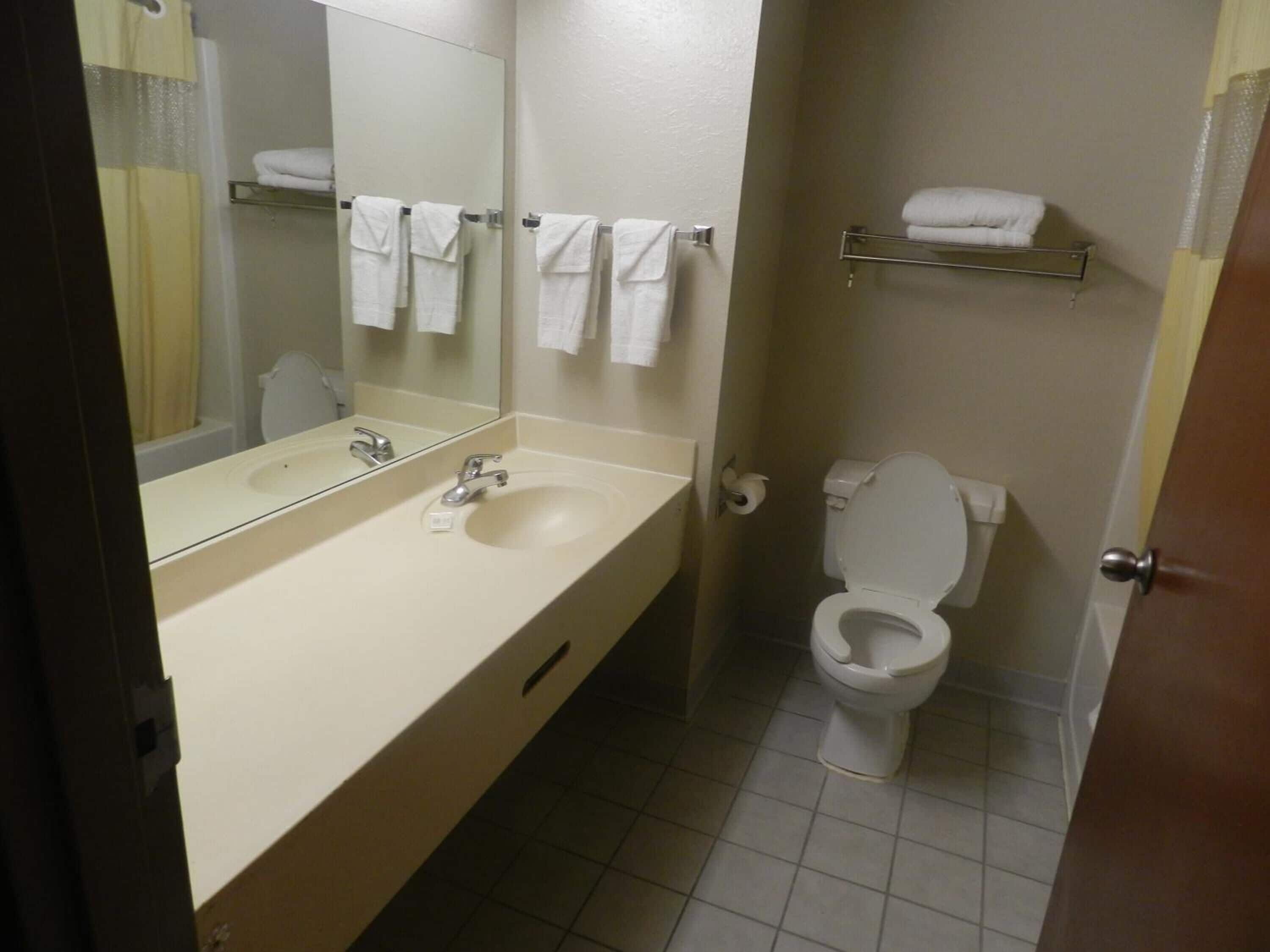 A bathroom with a sink, mirror, toilet, and towel rack.