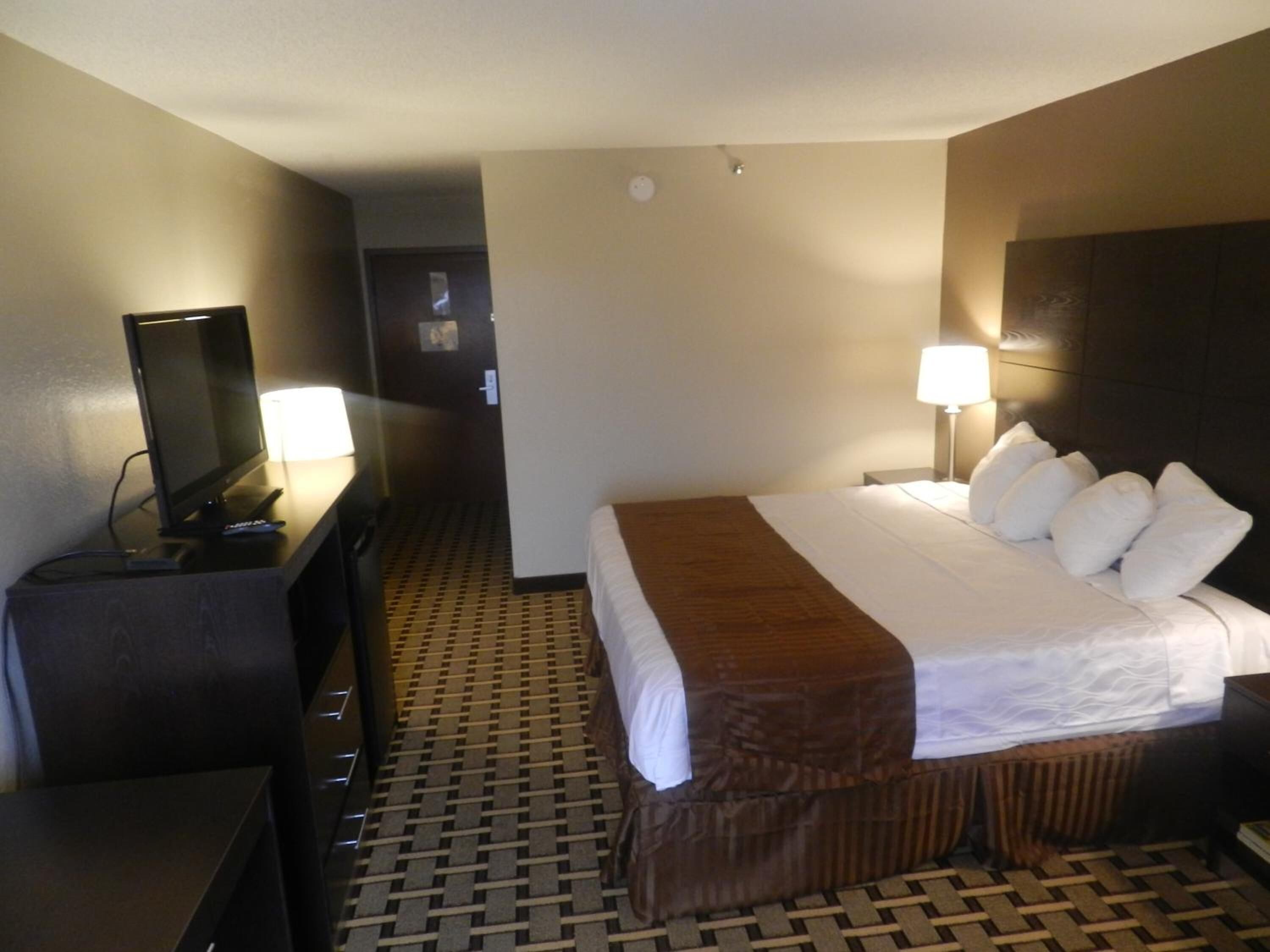 A hotel room with a bed, a TV, a desk, and a lamp.