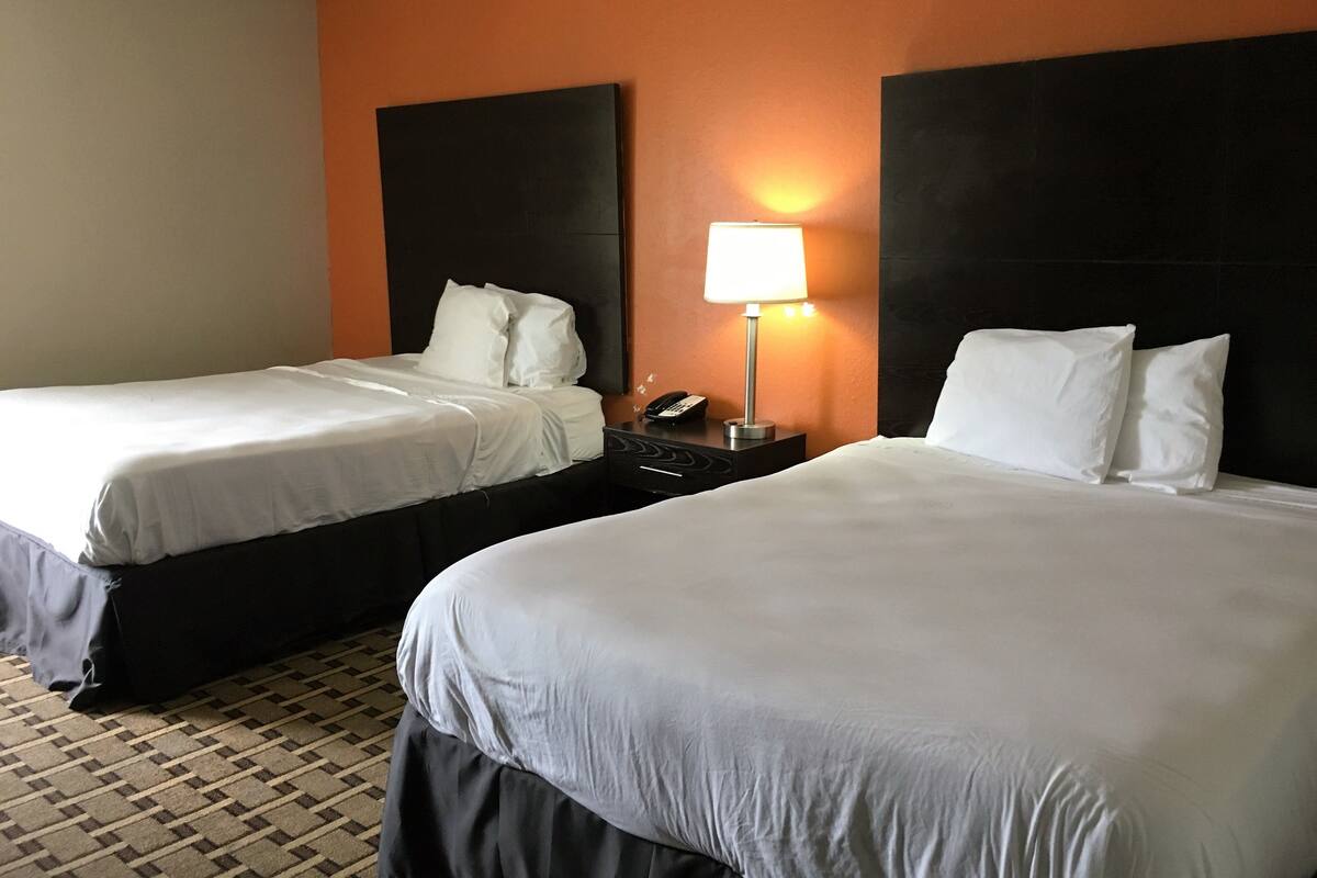 Una habitación de hotel con dos camas, una mesita de noche con lámpara y un teléfono.