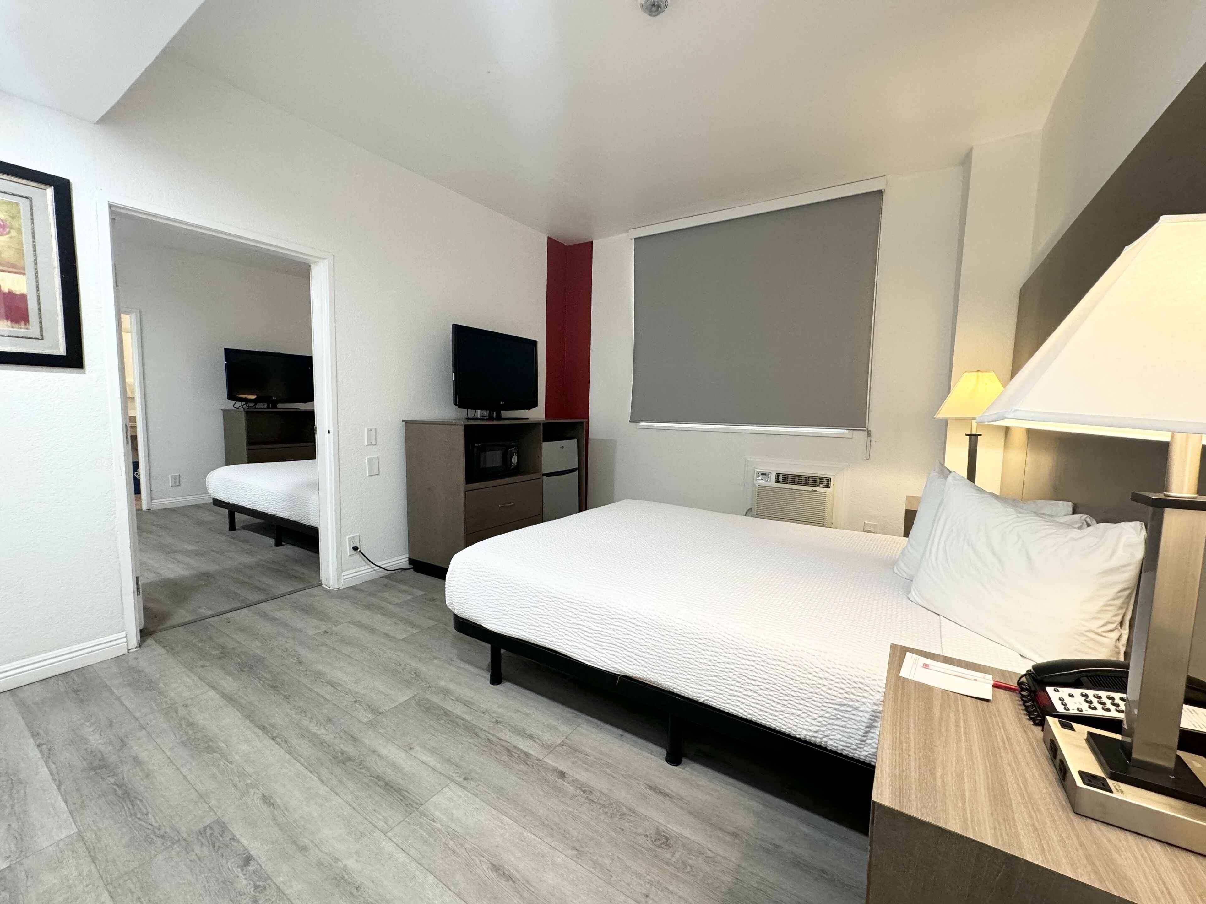 Un dormitorio con cama, mesita de noche, lámpara y teléfono.