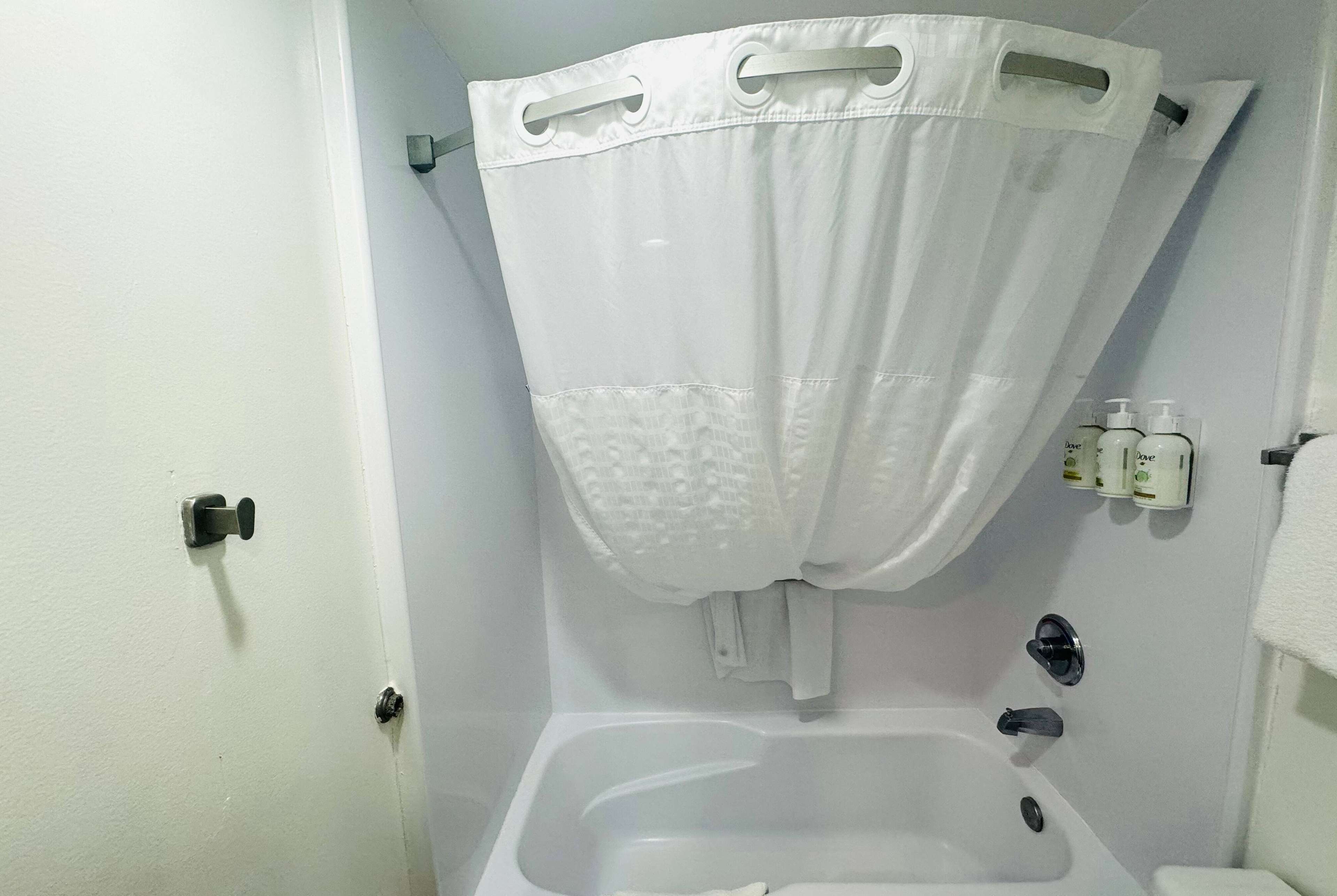 Une salle de bain avec une baignoire, un rideau de douche et un porte-serviettes avec des articles de toilette.