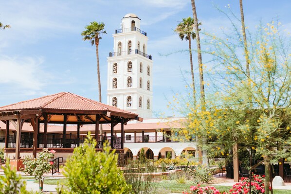 Un patio con una torre de campanas, un mirador y palmeras.