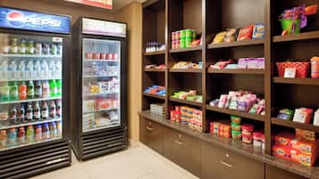 A grocery store with a Pepsi refrigerator, a market sign, and shelves stocked with snacks and beverages.