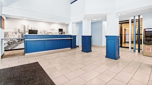 Un hall d’hôtel doté d’un comptoir d’accueil, d’une fresque représentant un paysage urbain et d’un design moderne.
