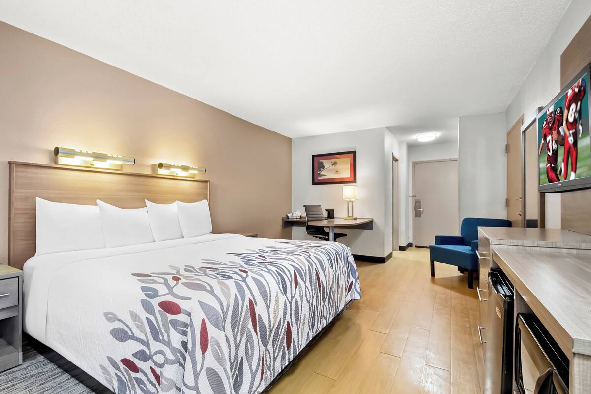 Una habitación de hotel con una cama grande, un escritorio, una silla y una kitchenette.