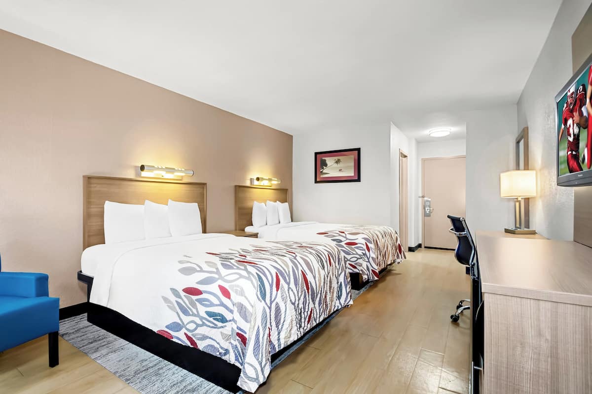 Una habitación de hotel con una cama grande, un escritorio, una silla y un televisor.