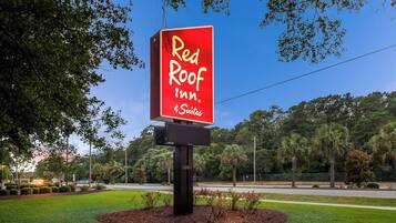 Placa da Red Roof Inn, com céu claro e árvores ao fundo.
